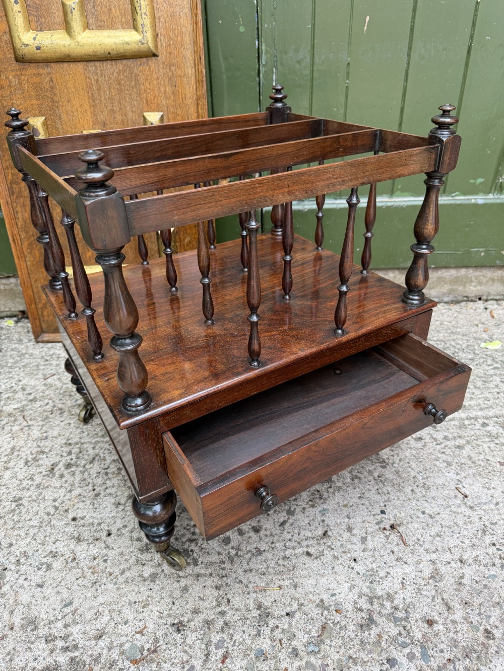 An early nineteenth-century George IV rosewood music canterbury featuring turned spindle divisions, a single base drawer, turned legs, and brass castors. View XV