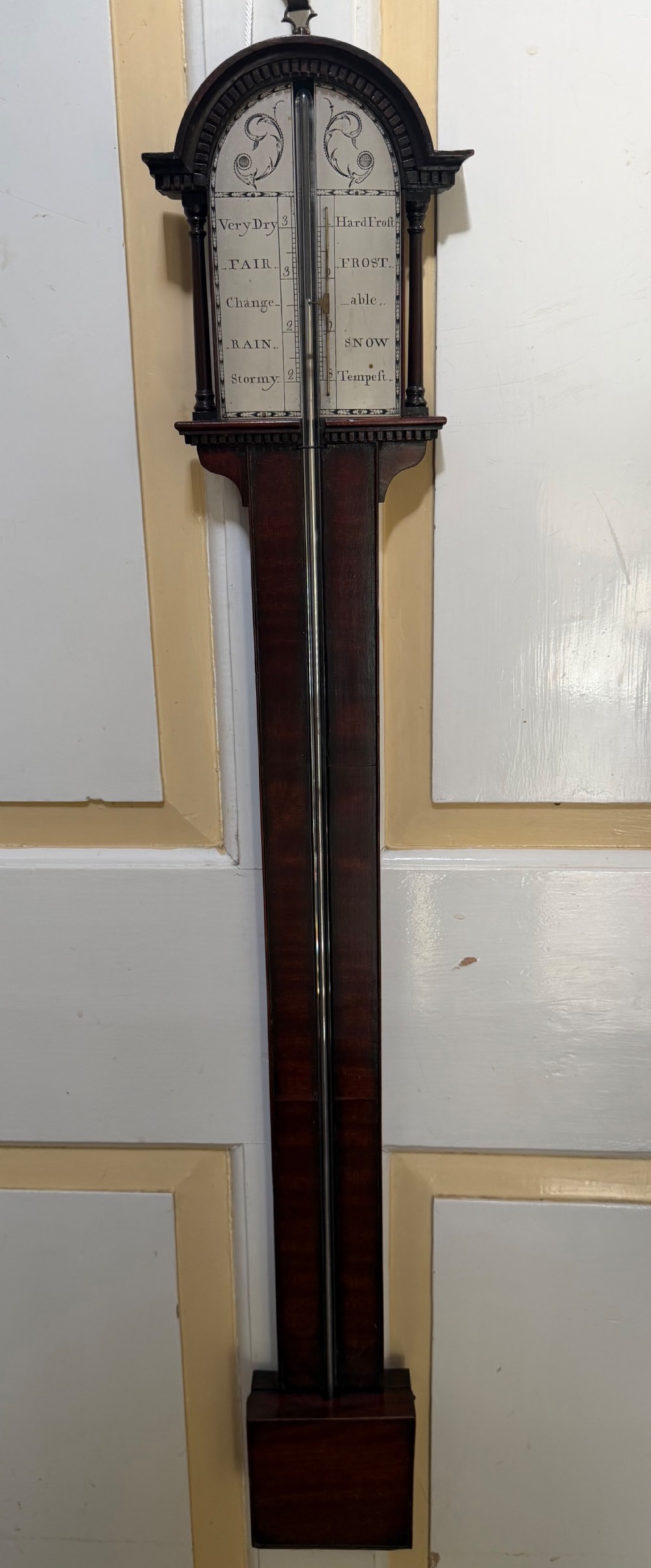 An eighteenth-century George III mahogany stick barometer with an architectural pediment and an engraved silvered dial.