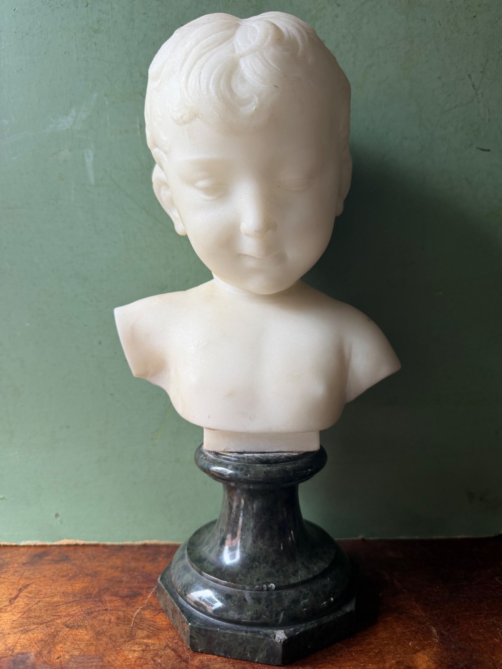 A late nineteenth-century white marble bust of a young boy set upon a dark green turned marble socle base.