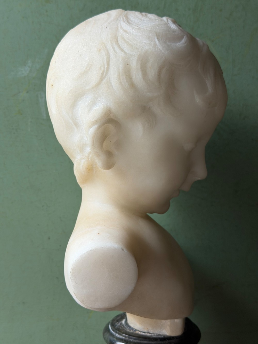 A late nineteenth-century white marble bust of a young boy set upon a dark green turned marble socle base. View II