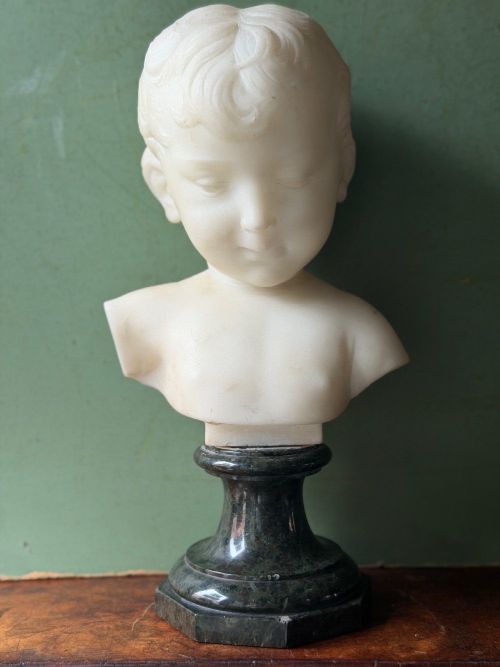 A late nineteenth-century white marble bust of a young boy set upon a dark green turned marble socle base. View III