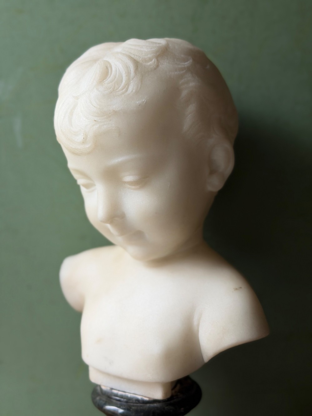 A late nineteenth-century white marble bust of a young boy set upon a dark green turned marble socle base. View IV