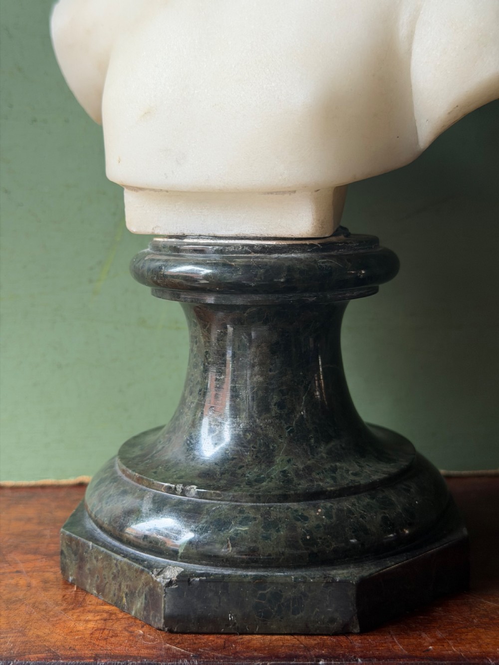 A late nineteenth-century white marble bust of a young boy set upon a dark green turned marble socle base. View V