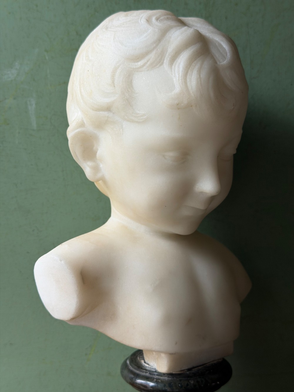 A late nineteenth-century white marble bust of a young boy set upon a dark green turned marble socle base. View VI