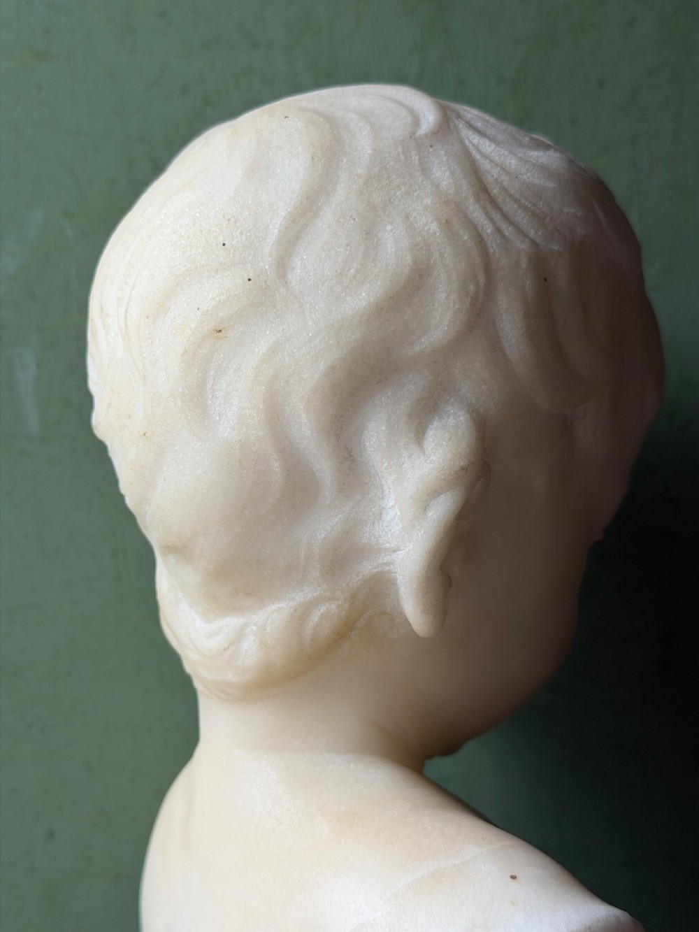 A late nineteenth-century white marble bust of a young boy set upon a dark green turned marble socle base. View VII