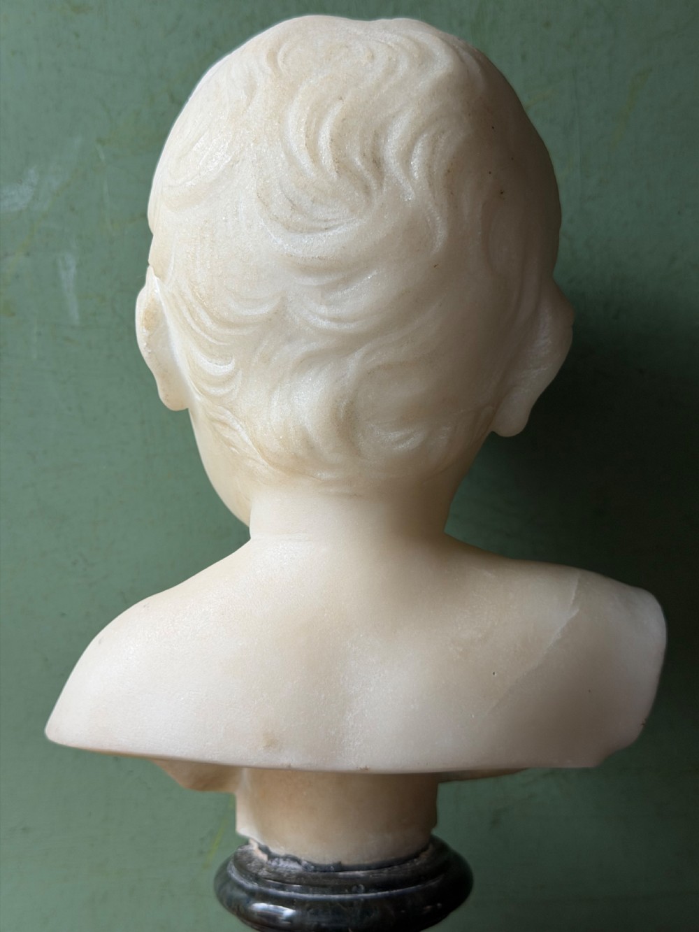 A late nineteenth-century white marble bust of a young boy set upon a dark green turned marble socle base. View VIII