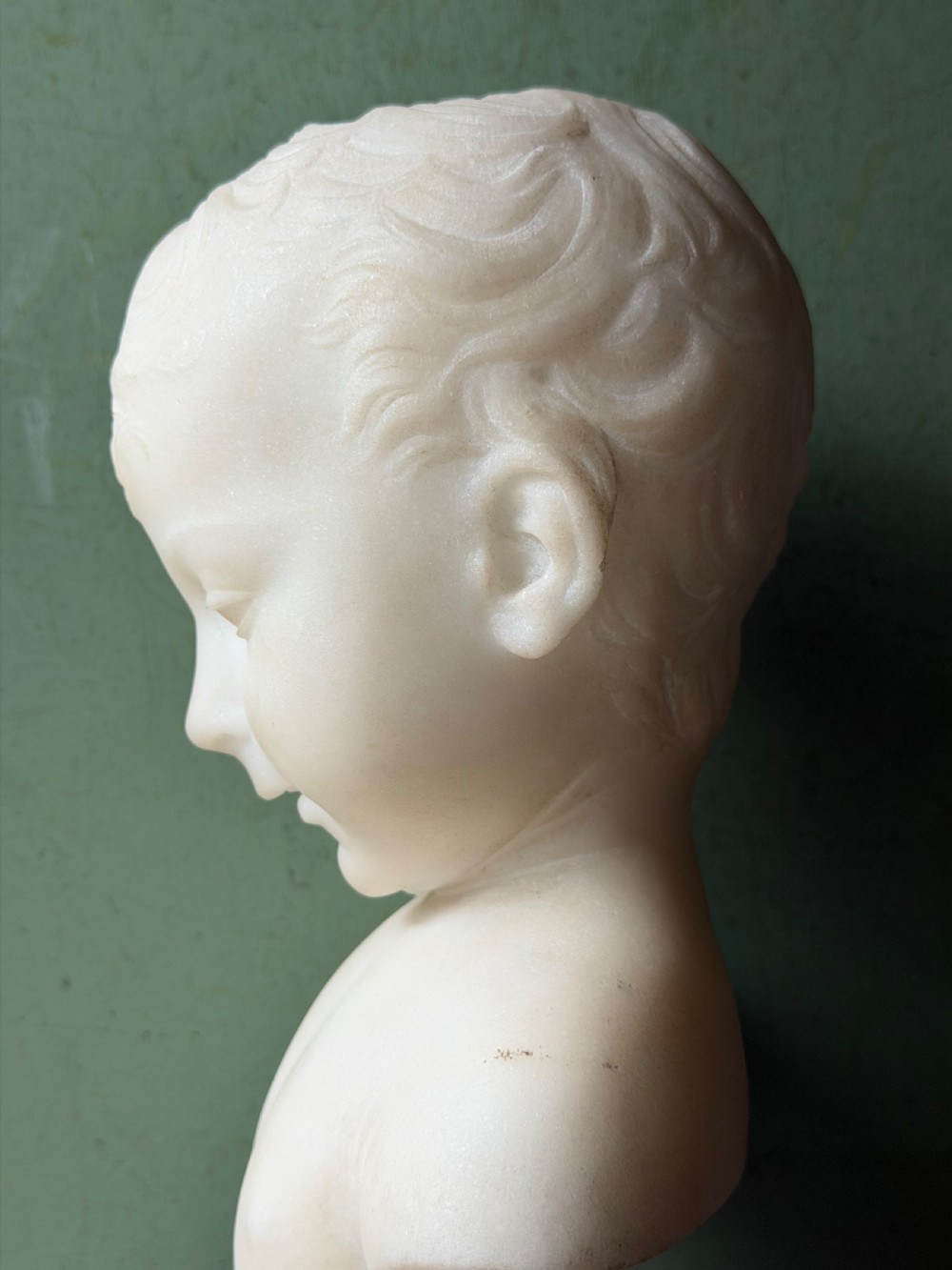 A late nineteenth-century white marble bust of a young boy set upon a dark green turned marble socle base. View IX