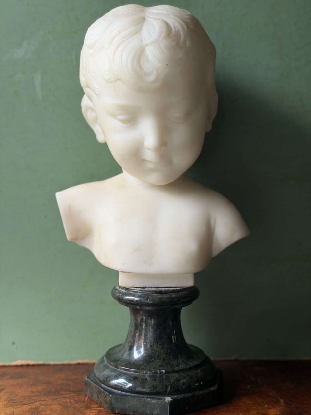 A late nineteenth-century white marble bust of a young boy set upon a dark green turned marble socle base. View X