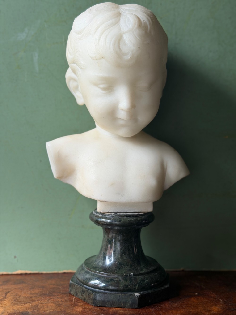 A late nineteenth-century white marble bust of a young boy set upon a dark green turned marble socle base. View XIII