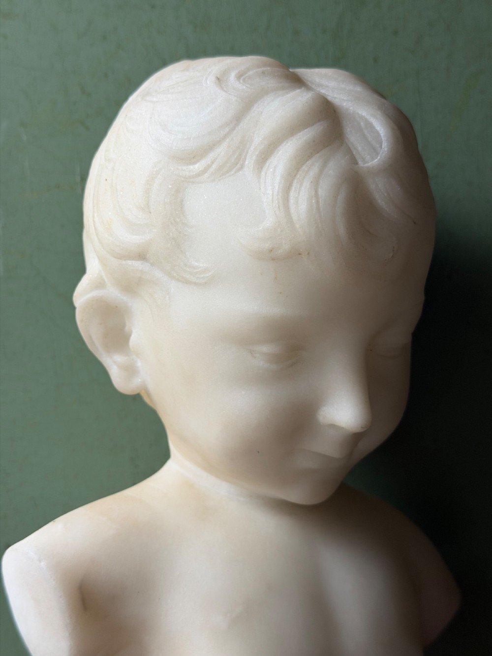 A late nineteenth-century white marble bust of a young boy set upon a dark green turned marble socle base. View XV