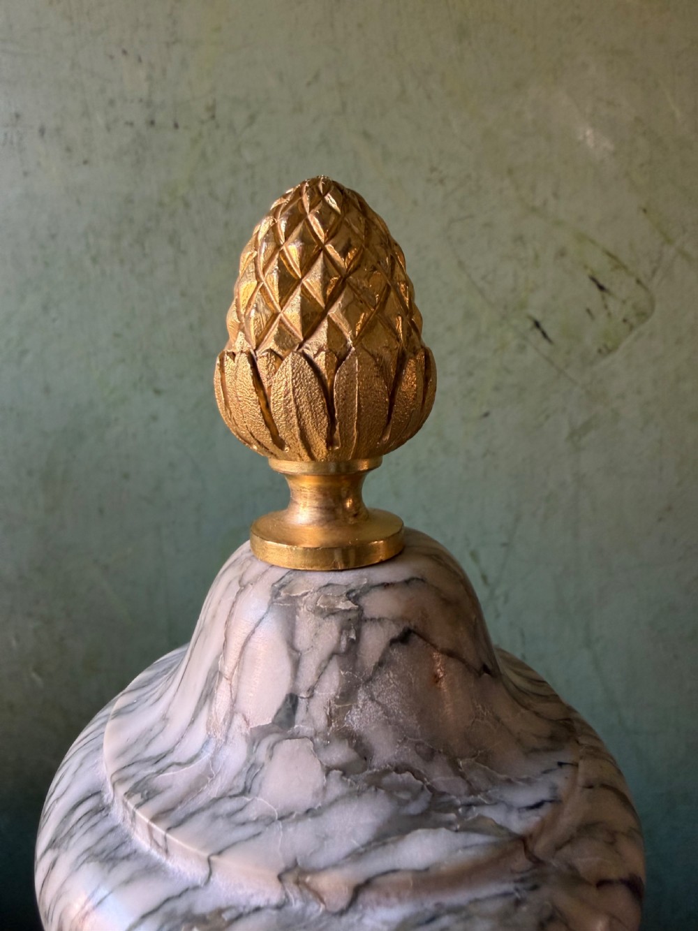 A pair of late 19th-century French Louis XVI style Campan vert marble urns adorned with gilt bronze ram head handles, floral swags, and pinecone finials. View V