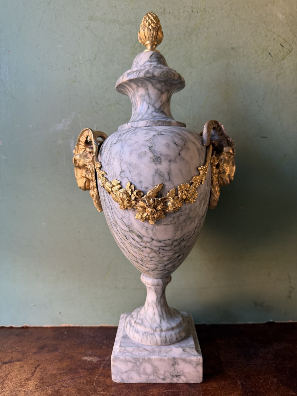 A pair of late 19th-century French Louis XVI style Campan vert marble urns adorned with gilt bronze ram head handles, floral swags, and pinecone finials. View XI