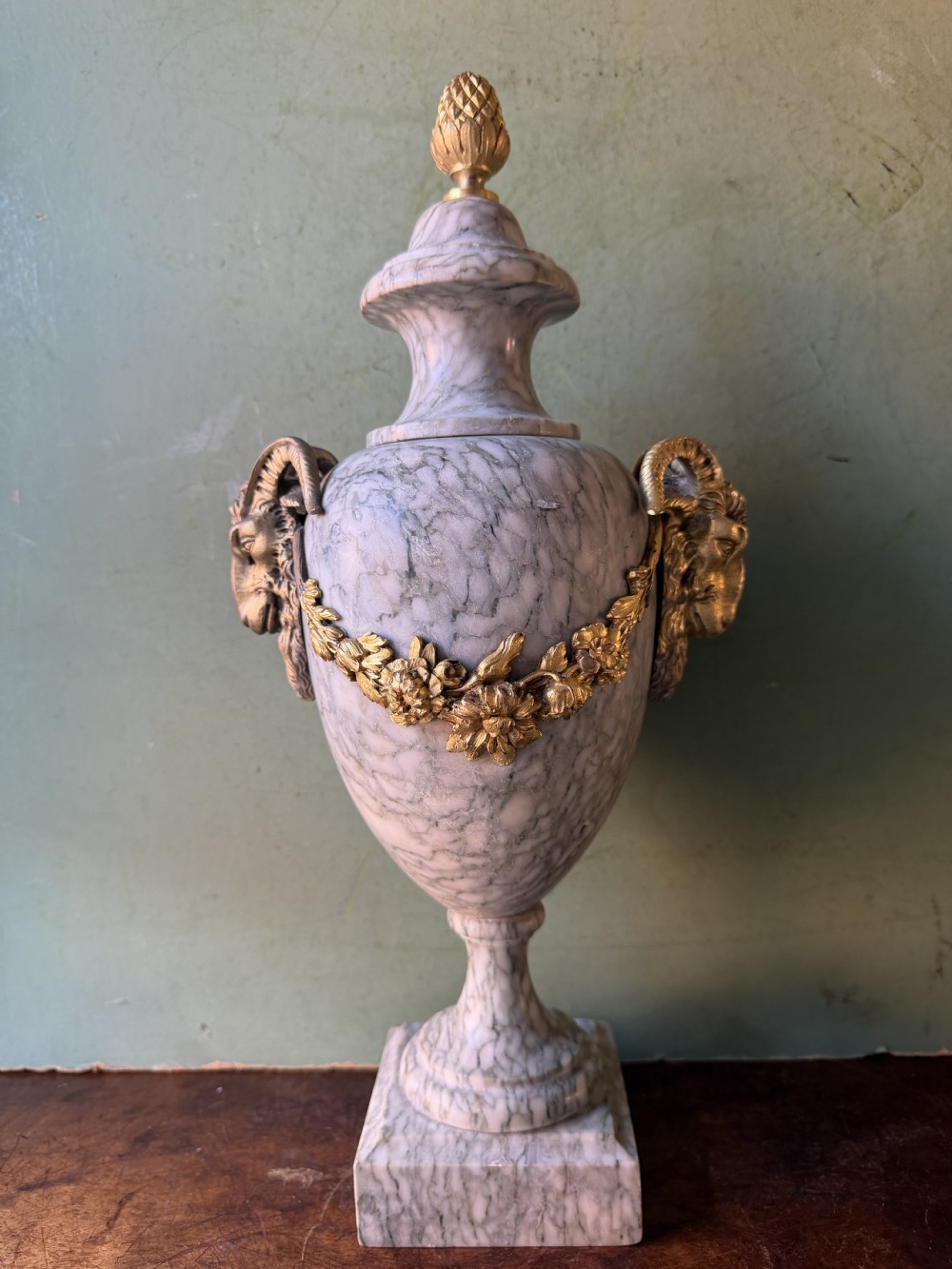 A pair of late 19th-century French Louis XVI style Campan vert marble urns adorned with gilt bronze ram head handles, floral swags, and pinecone finials. View XII