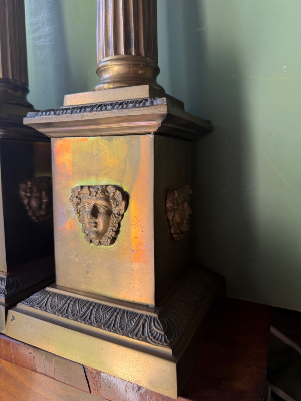 A pair of early twentieth-century brass table lamps featuring fluted classical columns, Corinthian capitals, and square pedestal bases decorated with cast face masks. View III