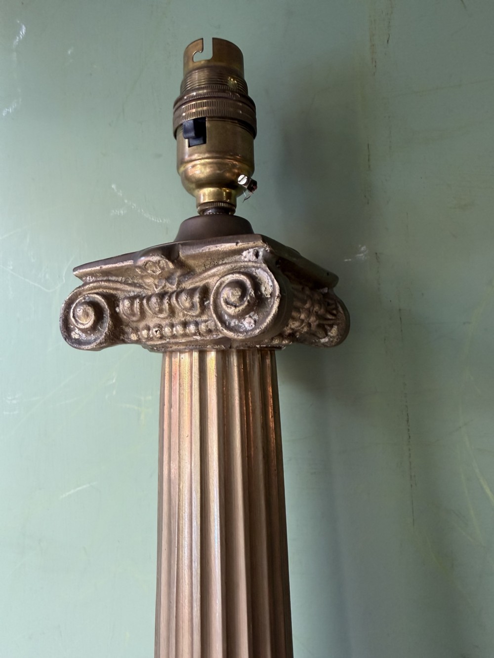 A pair of early twentieth-century brass table lamps featuring fluted classical columns, Corinthian capitals, and square pedestal bases decorated with cast face masks. View IV