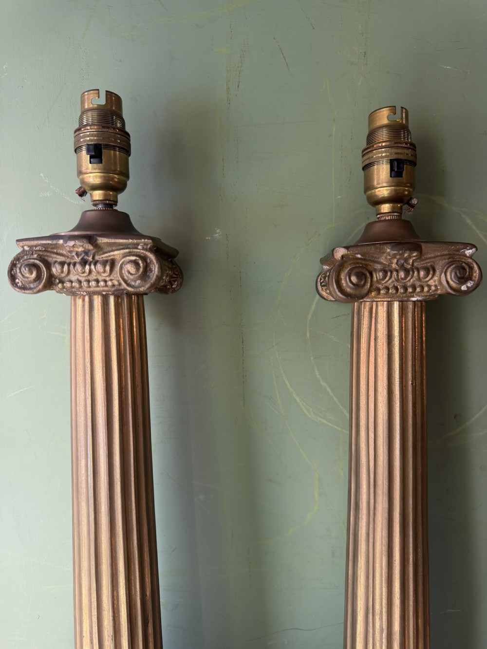 A pair of early twentieth-century brass table lamps featuring fluted classical columns, Corinthian capitals, and square pedestal bases decorated with cast face masks. View V