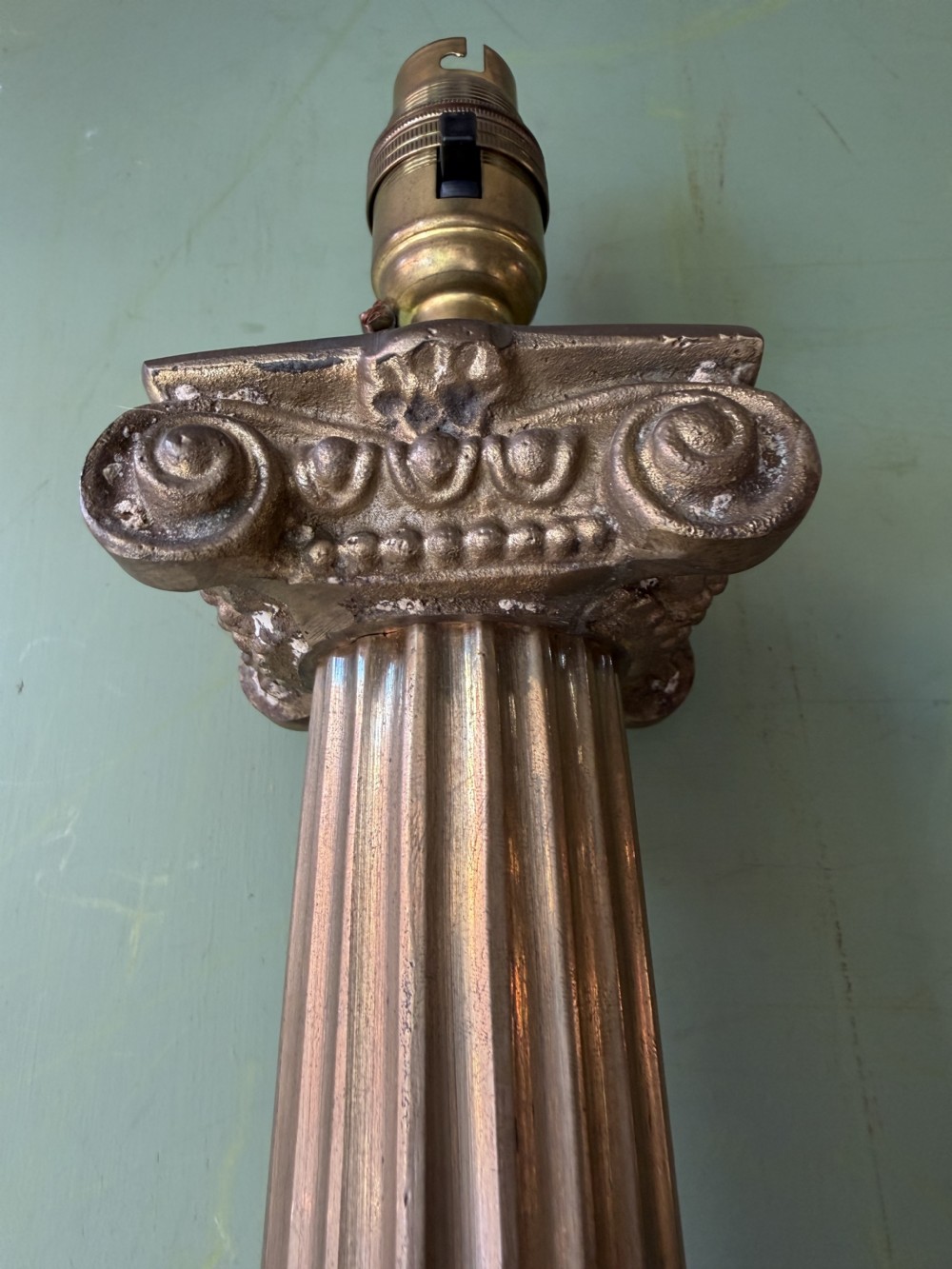 A pair of early twentieth-century brass table lamps featuring fluted classical columns, Corinthian capitals, and square pedestal bases decorated with cast face masks. View IX