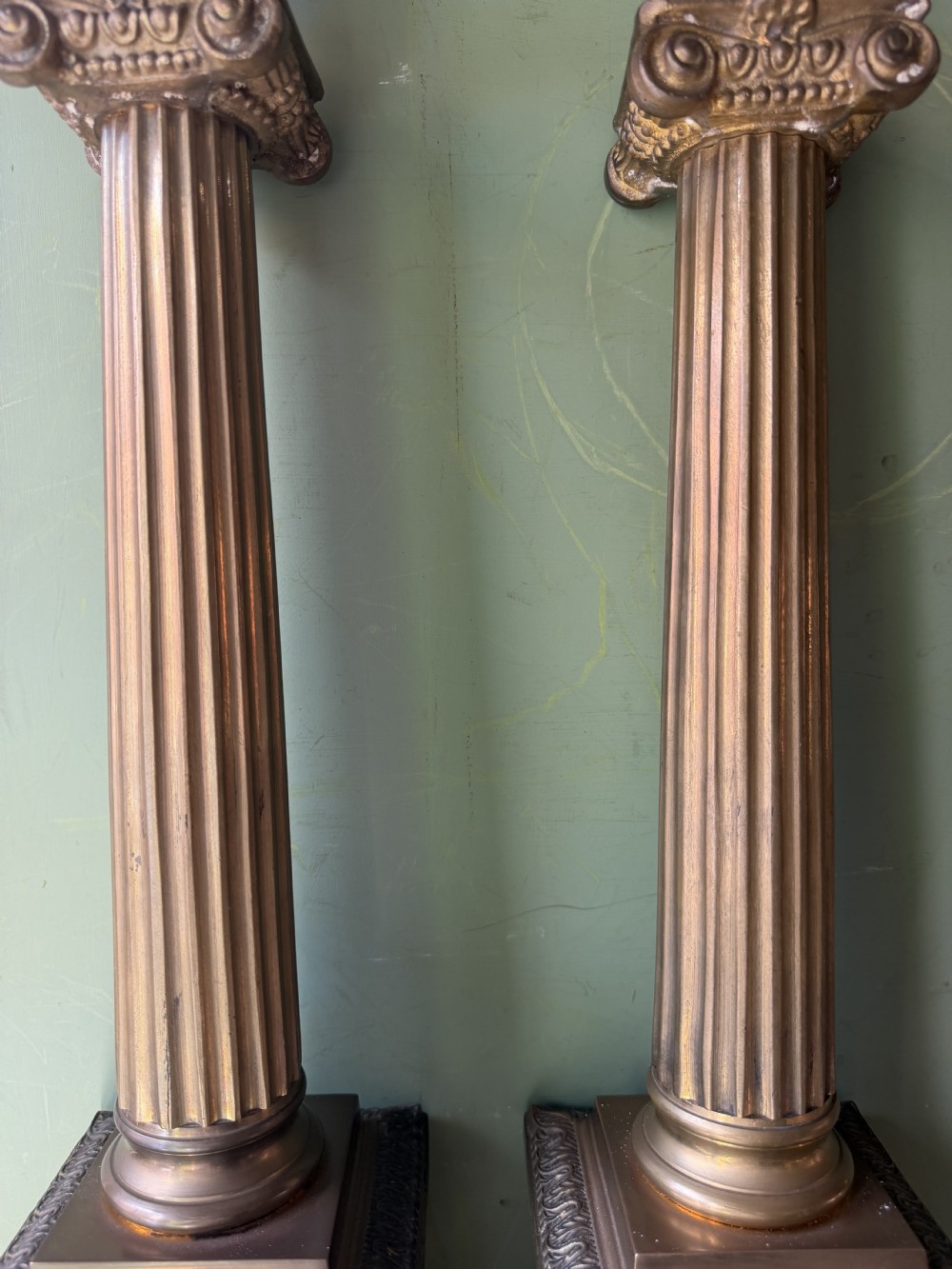 A pair of early twentieth-century brass table lamps featuring fluted classical columns, Corinthian capitals, and square pedestal bases decorated with cast face masks. View X