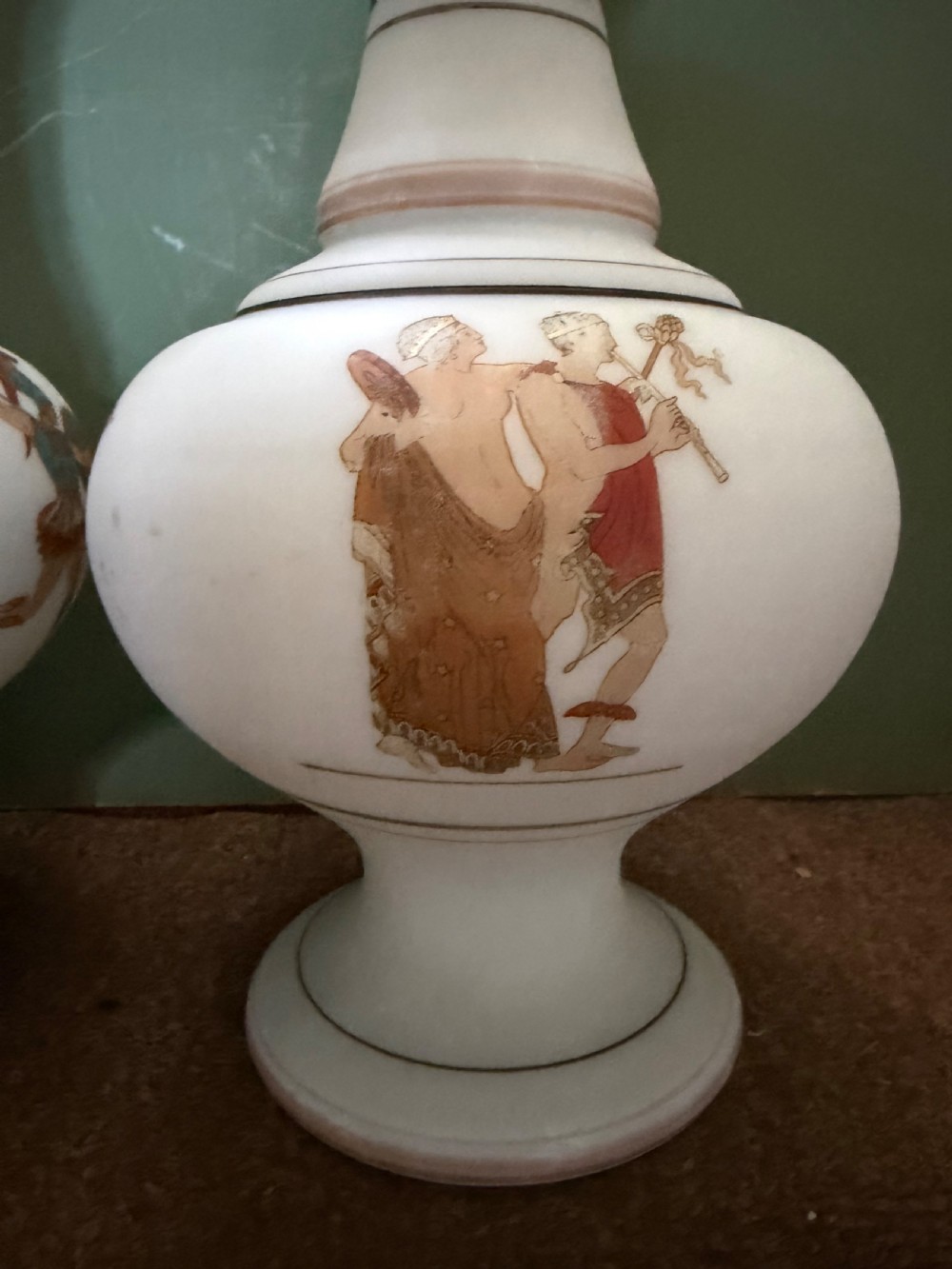 A pair of white opaline glass vases featuring flared necks decorated with orange Greek key patterns and baluster bodies painted with classical Grecian warrior figures. View VI