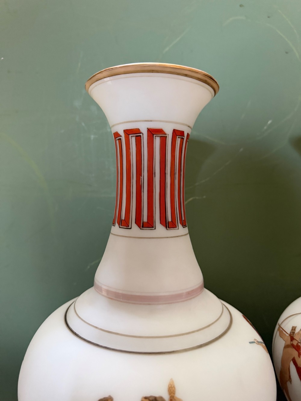 A pair of white opaline glass vases featuring flared necks decorated with orange Greek key patterns and baluster bodies painted with classical Grecian warrior figures. View VII