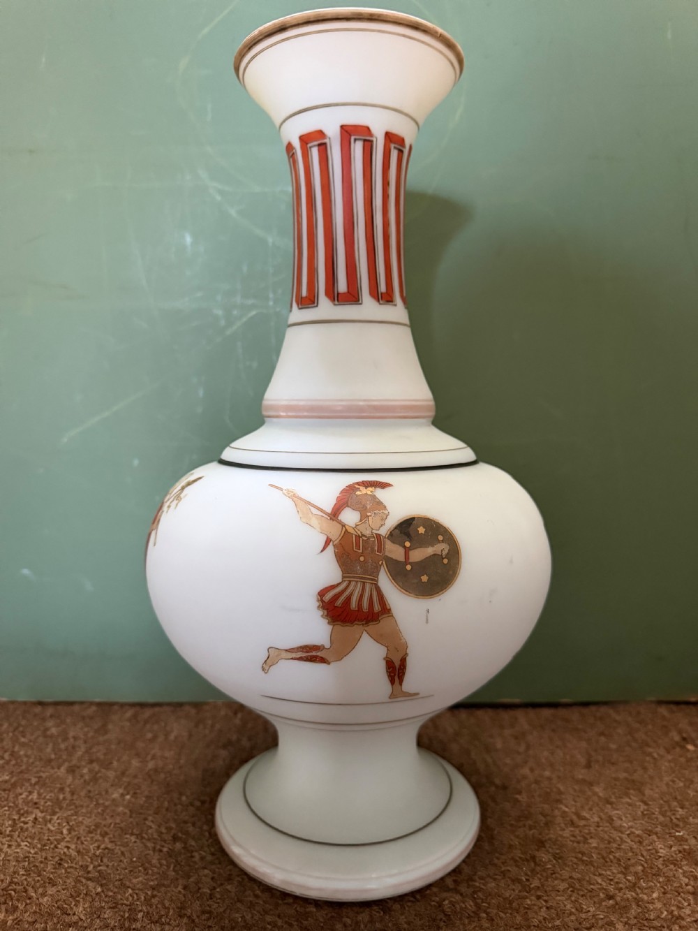 A pair of white opaline glass vases featuring flared necks decorated with orange Greek key patterns and baluster bodies painted with classical Grecian warrior figures. View IX