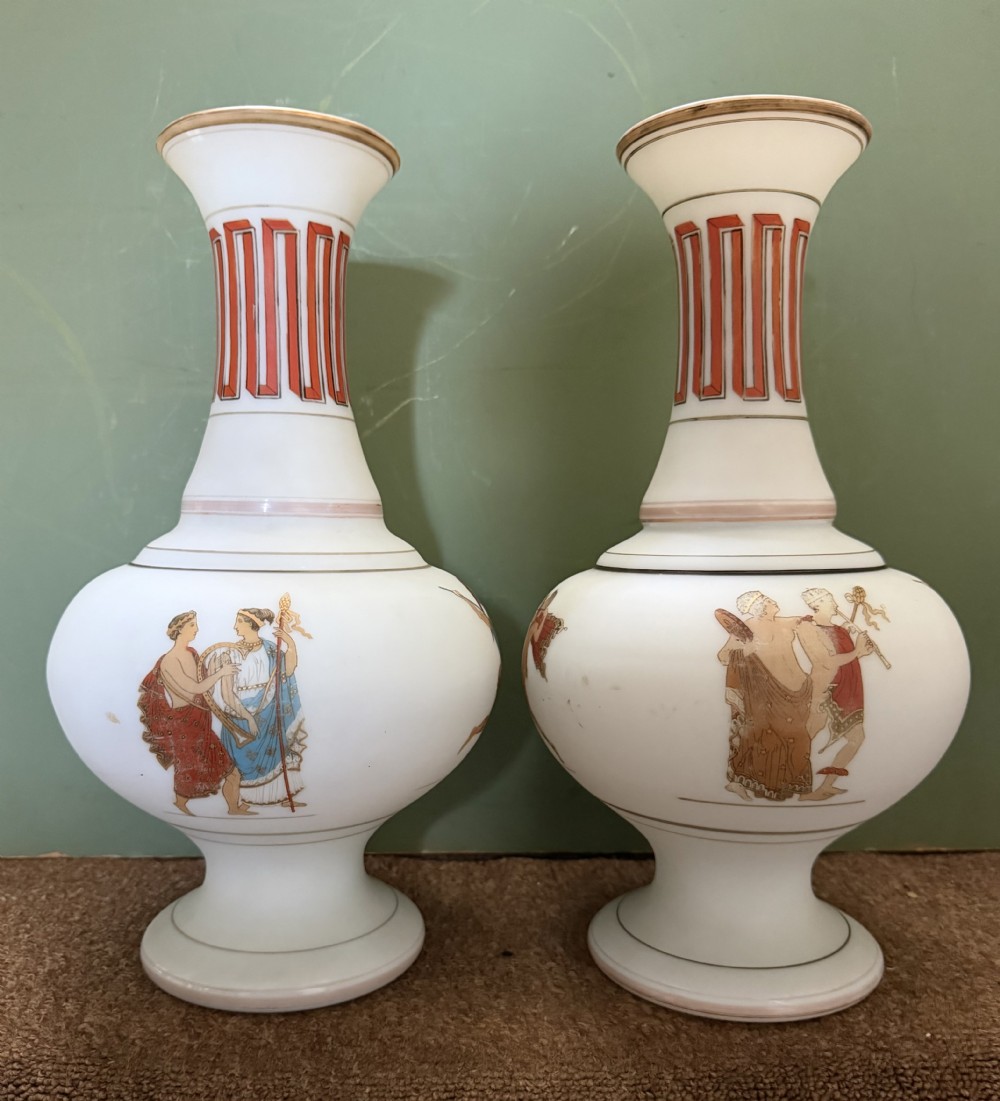 A pair of white opaline glass vases featuring flared necks decorated with orange Greek key patterns and baluster bodies painted with classical Grecian warrior figures. View IV