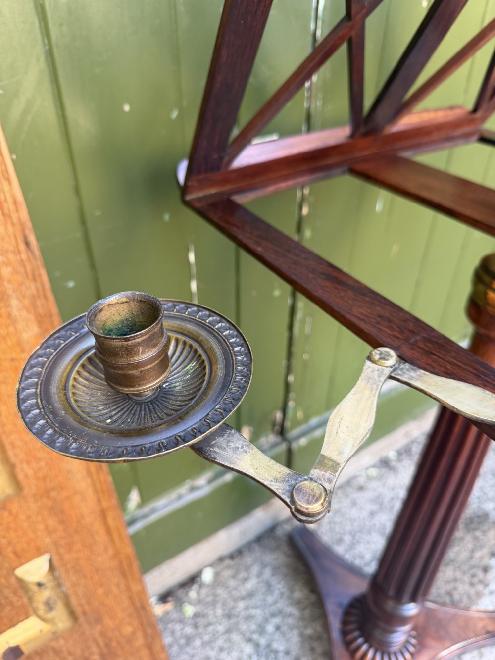 An early 19th-century Regency rosewood duet music stand featuring an adjustable double-sided frame with cross-latticed supports, twin brass candle sconces, a fluted column, and a tripartite base on castors. View III