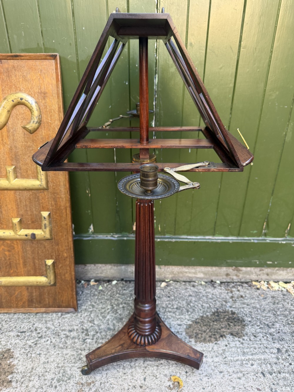 An early 19th-century Regency rosewood duet music stand featuring an adjustable double-sided frame with cross-latticed supports, twin brass candle sconces, a fluted column, and a tripartite base on castors. View IV