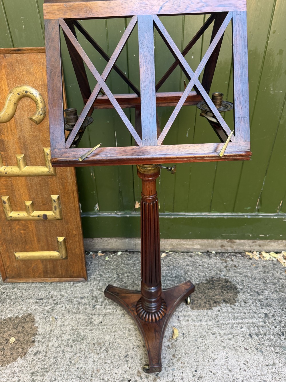 An early 19th-century Regency rosewood duet music stand featuring an adjustable double-sided frame with cross-latticed supports, twin brass candle sconces, a fluted column, and a tripartite base on castors. View VIII