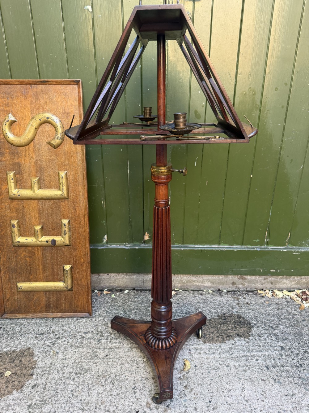 An early 19th-century Regency rosewood duet music stand featuring an adjustable double-sided frame with cross-latticed supports, twin brass candle sconces, a fluted column, and a tripartite base on castors. View XIII