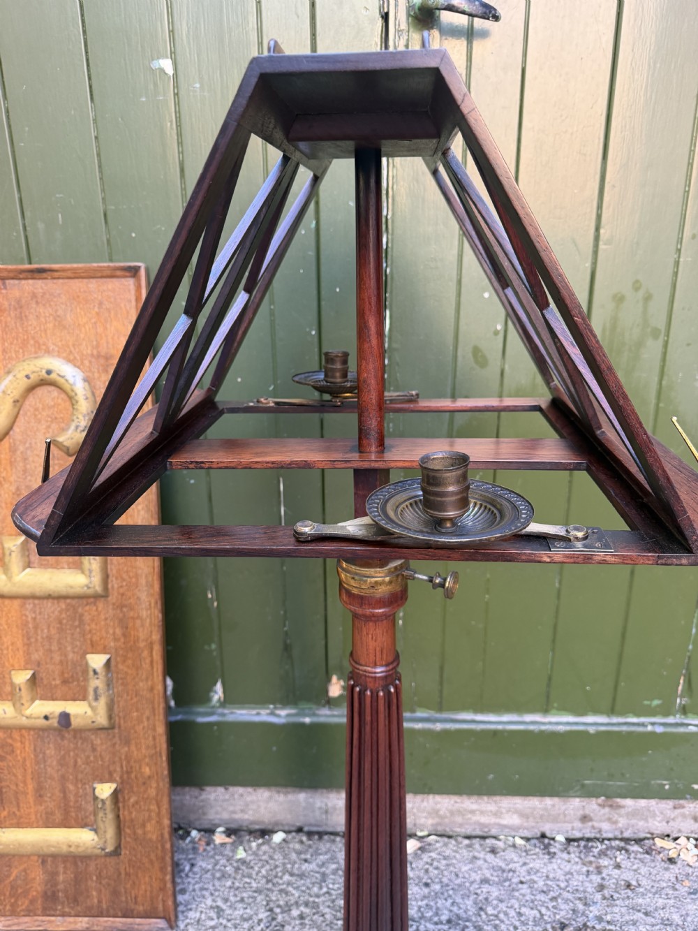 An early 19th-century Regency rosewood duet music stand featuring an adjustable double-sided frame with cross-latticed supports, twin brass candle sconces, a fluted column, and a tripartite base on castors. View XV