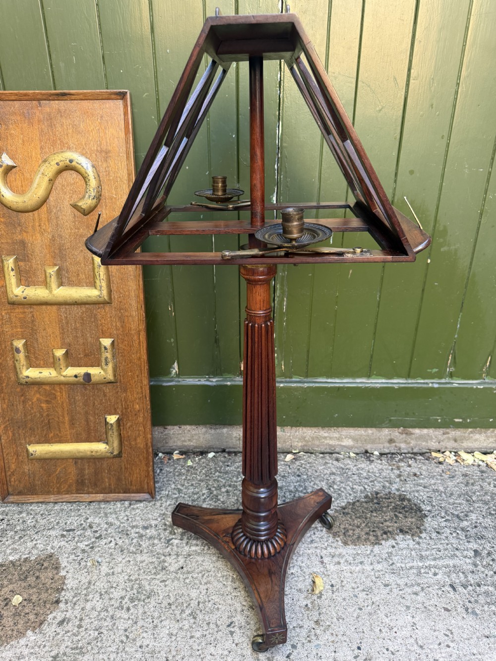 An early 19th-century Regency rosewood duet music stand featuring an adjustable double-sided frame with cross-latticed supports, twin brass candle sconces, a fluted column, and a tripartite base on castors. View XX