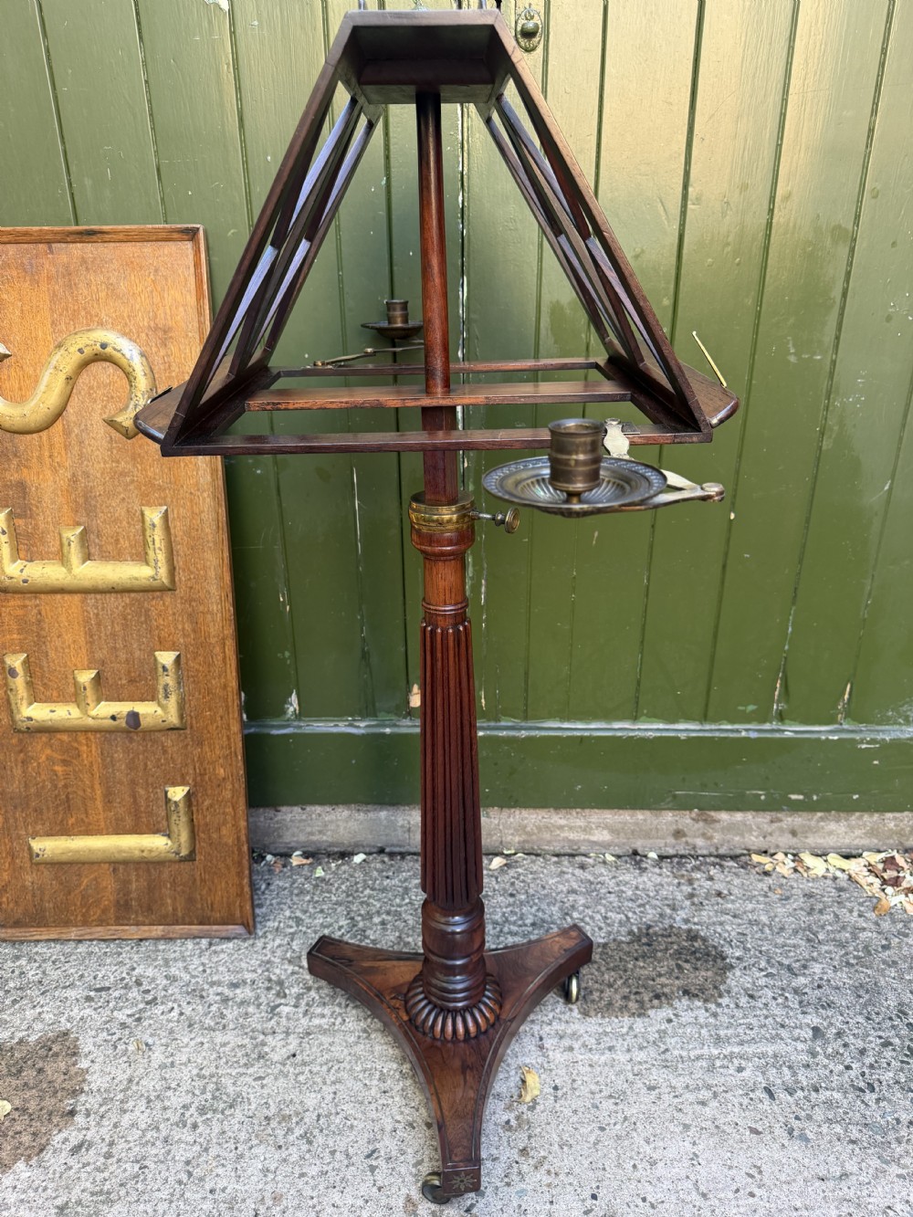 An early 19th-century Regency rosewood duet music stand featuring an adjustable double-sided frame with cross-latticed supports, twin brass candle sconces, a fluted column, and a tripartite base on castors. View XXII