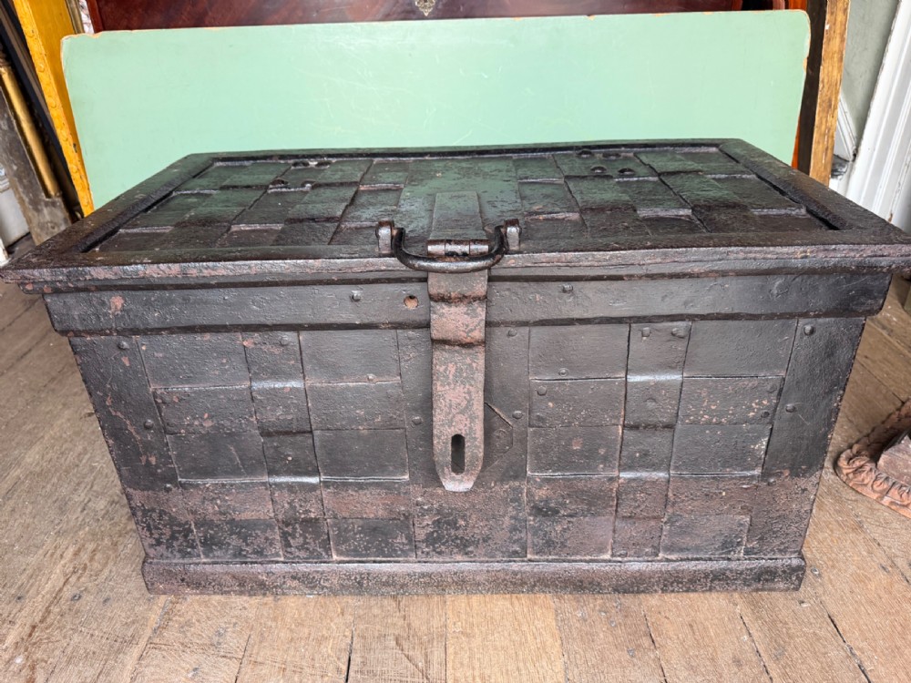 A rectangular late seventeenth-century wrought iron strongbox with criss-crossing riveted bands and a heavy central iron locking hasp.
