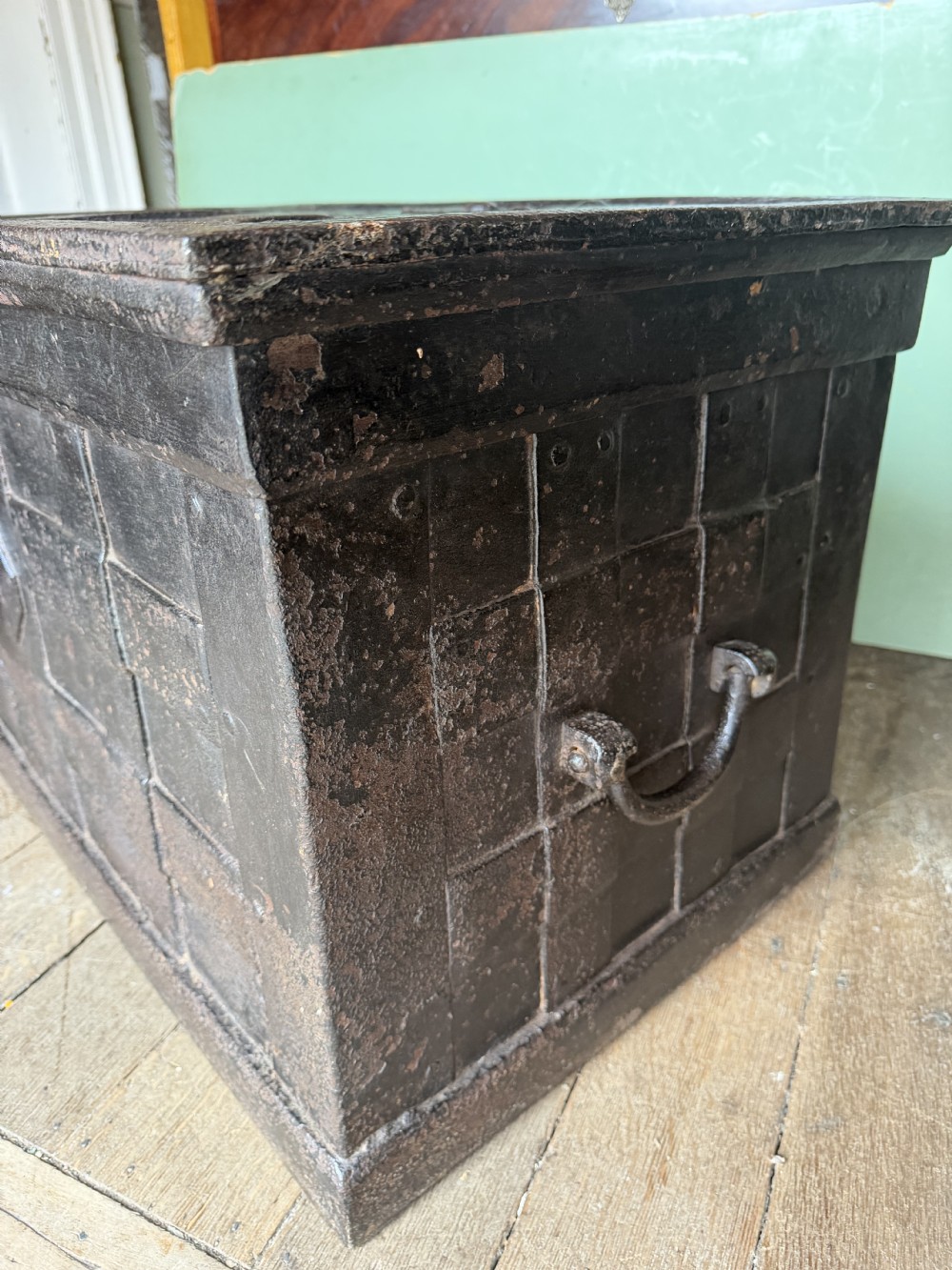 A rectangular late seventeenth-century wrought iron strongbox with criss-crossing riveted bands and a heavy central iron locking hasp. View IX