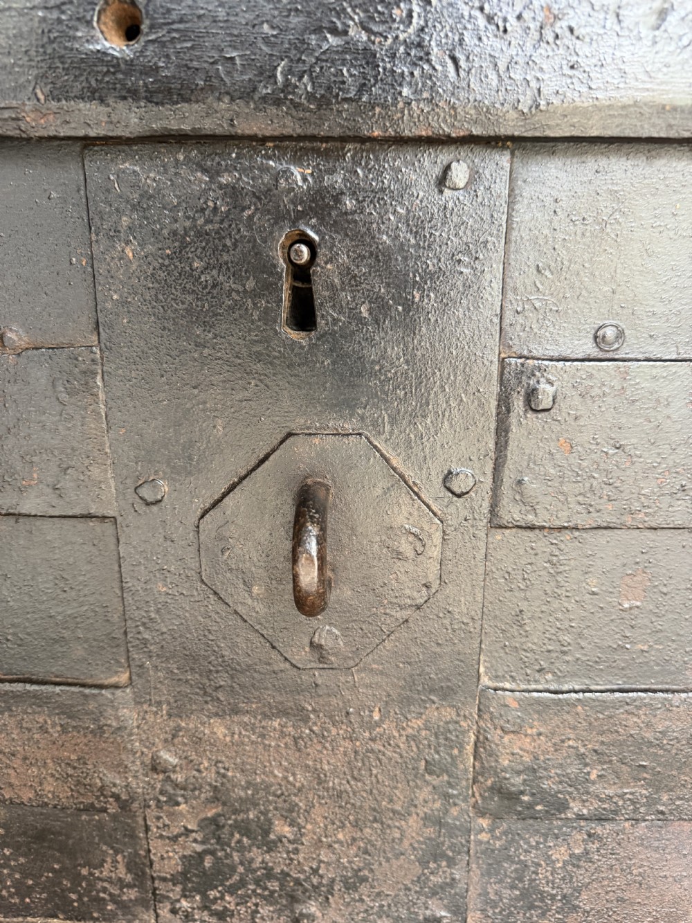 A rectangular late seventeenth-century wrought iron strongbox with criss-crossing riveted bands and a heavy central iron locking hasp. View XII