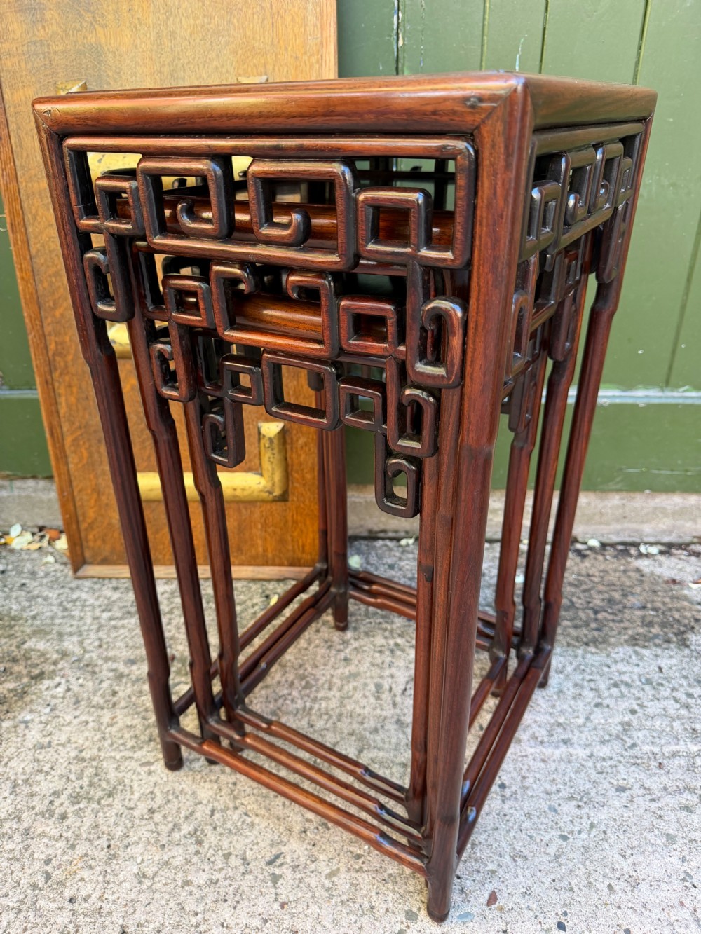 A set of three graduated dark hardwood Chinese nesting tables featuring openwork carved fretwork aprons and straight legs with perimeter stretchers. View II