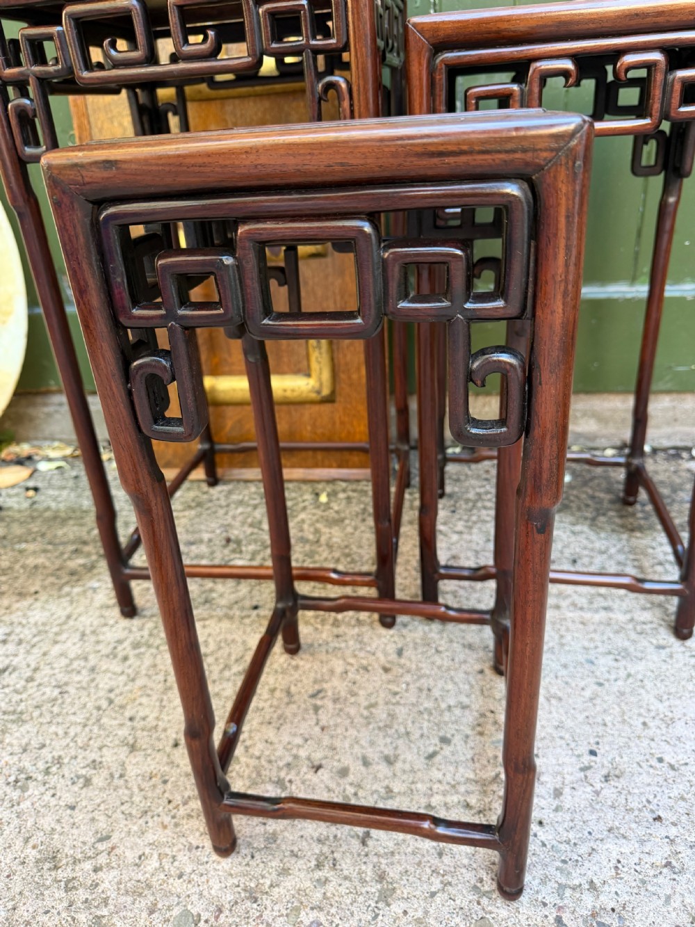 A set of three graduated dark hardwood Chinese nesting tables featuring openwork carved fretwork aprons and straight legs with perimeter stretchers. View IV
