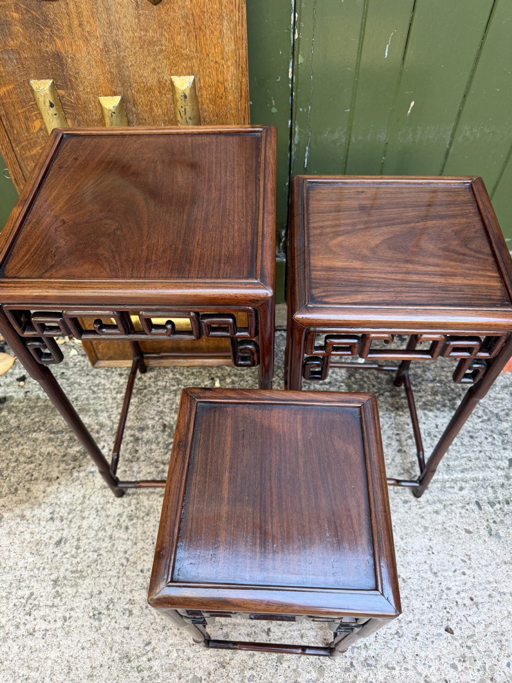 A set of three graduated dark hardwood Chinese nesting tables featuring openwork carved fretwork aprons and straight legs with perimeter stretchers. View VI