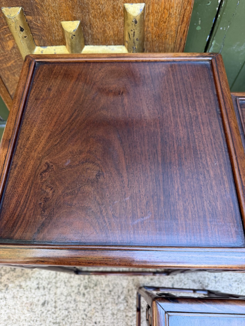 A set of three graduated dark hardwood Chinese nesting tables featuring openwork carved fretwork aprons and straight legs with perimeter stretchers. View VII