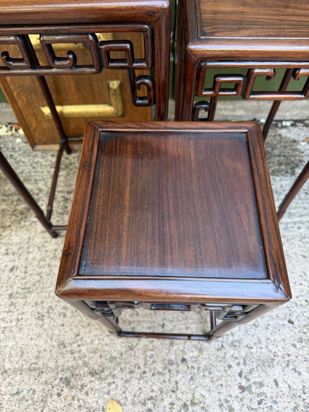 A set of three graduated dark hardwood Chinese nesting tables featuring openwork carved fretwork aprons and straight legs with perimeter stretchers. View VIII