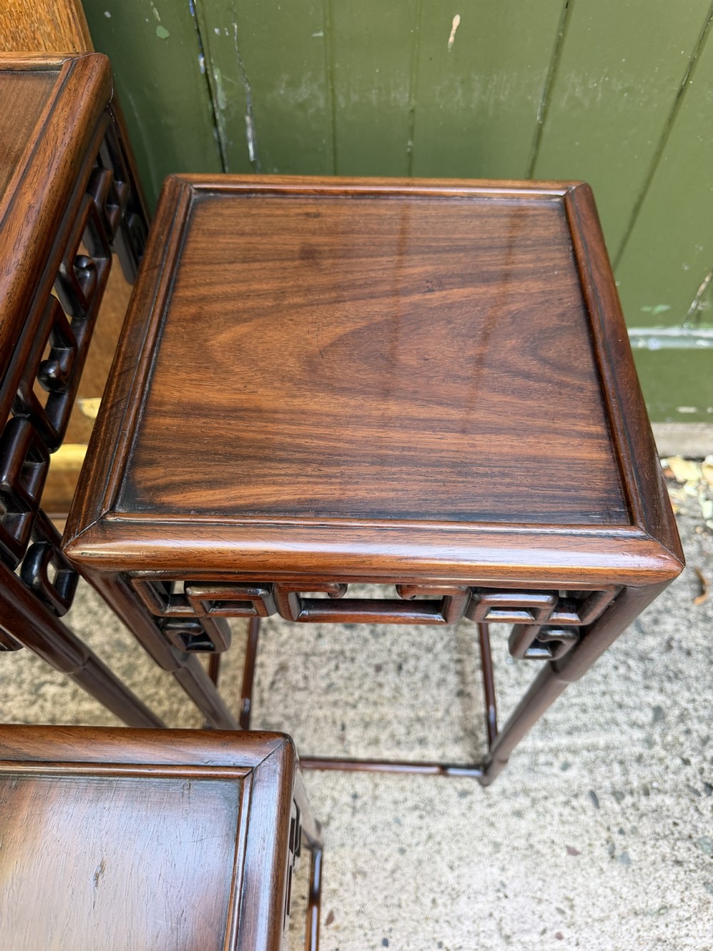 A set of three graduated dark hardwood Chinese nesting tables featuring openwork carved fretwork aprons and straight legs with perimeter stretchers. View IX