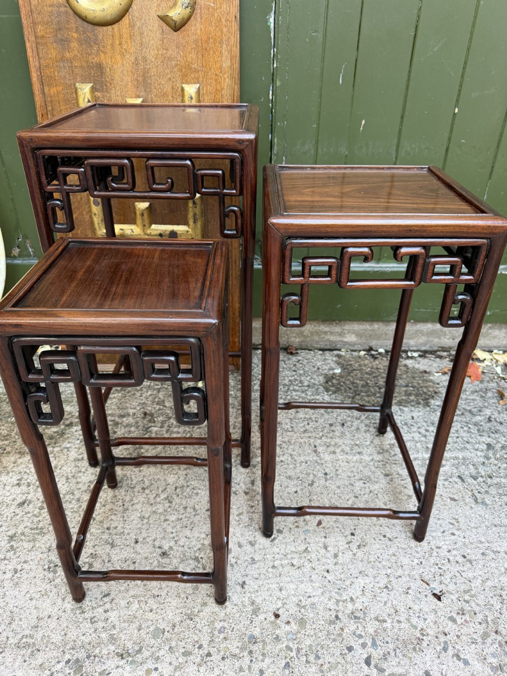 A set of three graduated dark hardwood Chinese nesting tables featuring openwork carved fretwork aprons and straight legs with perimeter stretchers. View X