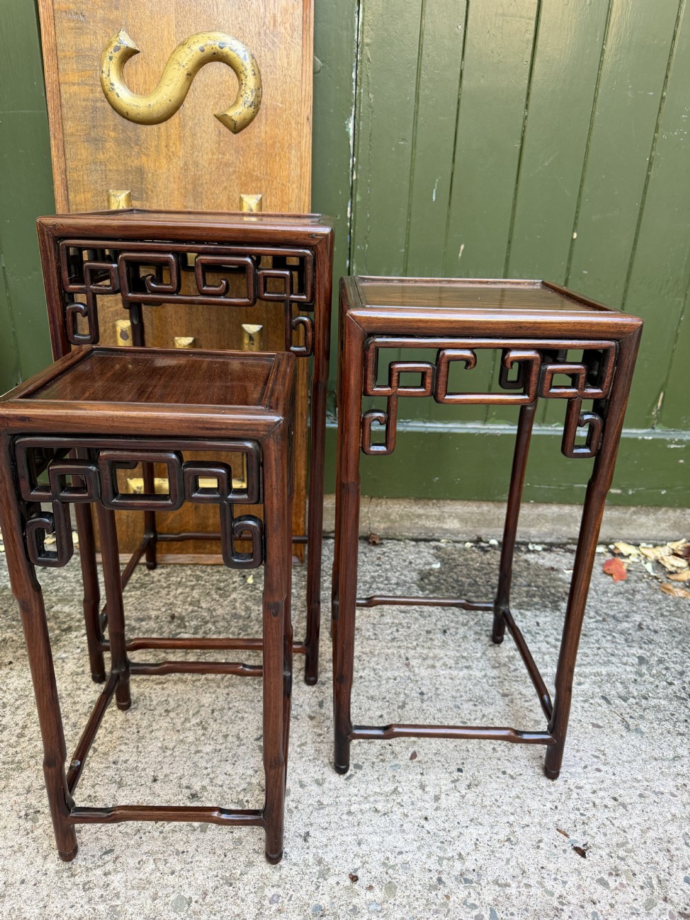 A set of three graduated dark hardwood Chinese nesting tables featuring openwork carved fretwork aprons and straight legs with perimeter stretchers. View XI
