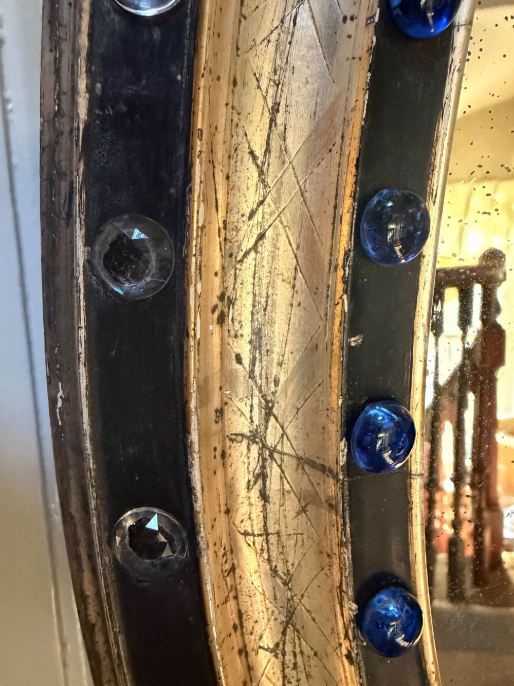 A nineteenth-century Irish oval wall mirror featuring an ebonised frame inset with clear facetted glass jewels, an inner silver-gilt band, and cobalt blue glass cabochons. View II