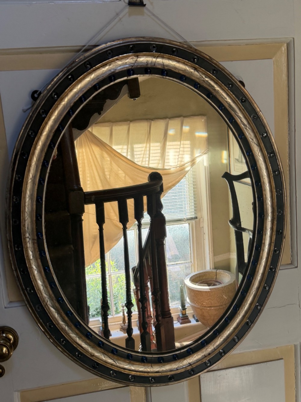 A nineteenth-century Irish oval wall mirror featuring an ebonised frame inset with clear facetted glass jewels, an inner silver-gilt band, and cobalt blue glass cabochons. View IV