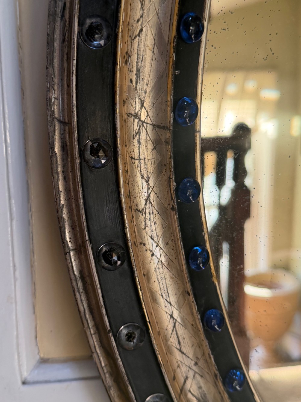 A nineteenth-century Irish oval wall mirror featuring an ebonised frame inset with clear facetted glass jewels, an inner silver-gilt band, and cobalt blue glass cabochons. View VI
