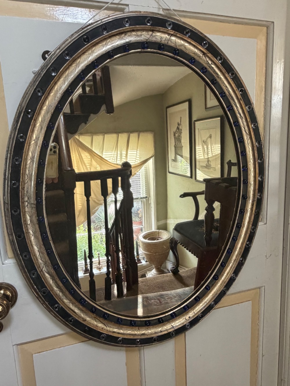 A nineteenth-century Irish oval wall mirror featuring an ebonised frame inset with clear facetted glass jewels, an inner silver-gilt band, and cobalt blue glass cabochons. View IV