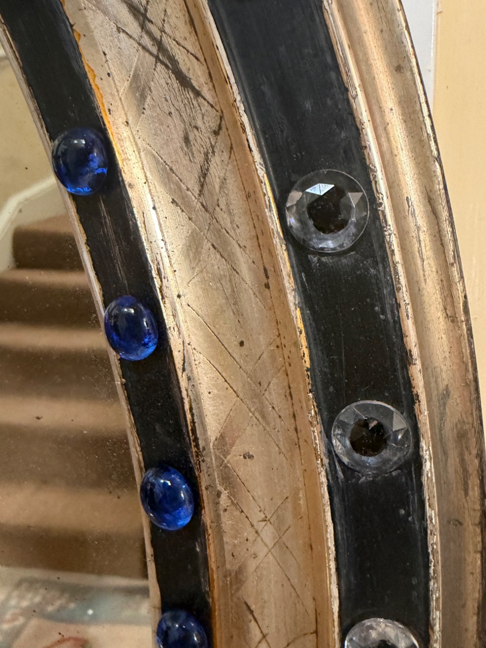 A nineteenth-century Irish oval wall mirror featuring an ebonised frame inset with clear facetted glass jewels, an inner silver-gilt band, and cobalt blue glass cabochons. View V