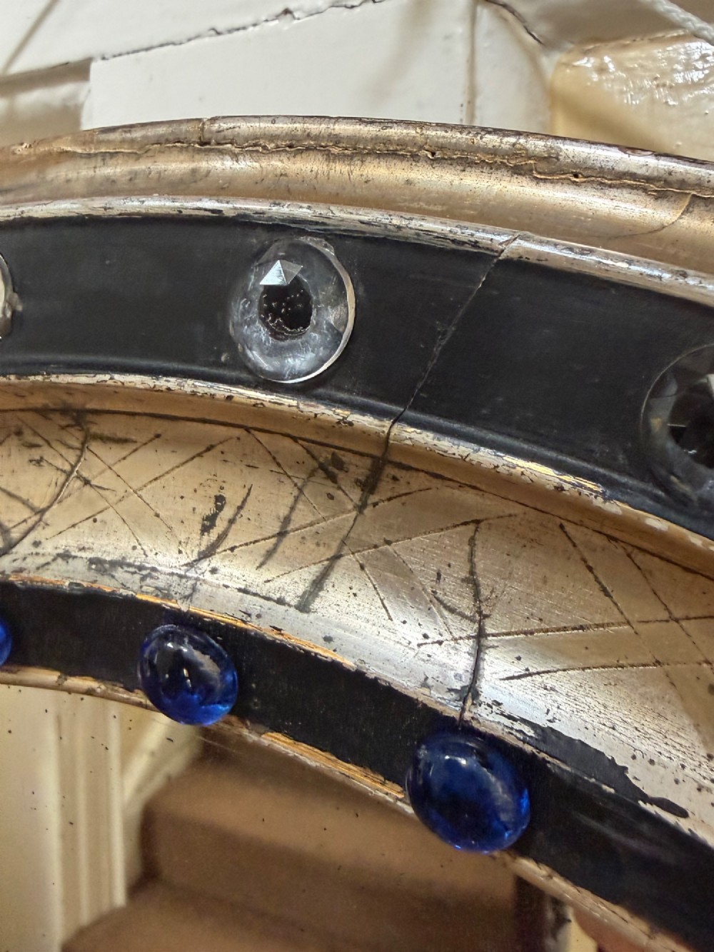 A nineteenth-century Irish oval wall mirror featuring an ebonised frame inset with clear facetted glass jewels, an inner silver-gilt band, and cobalt blue glass cabochons. View VI